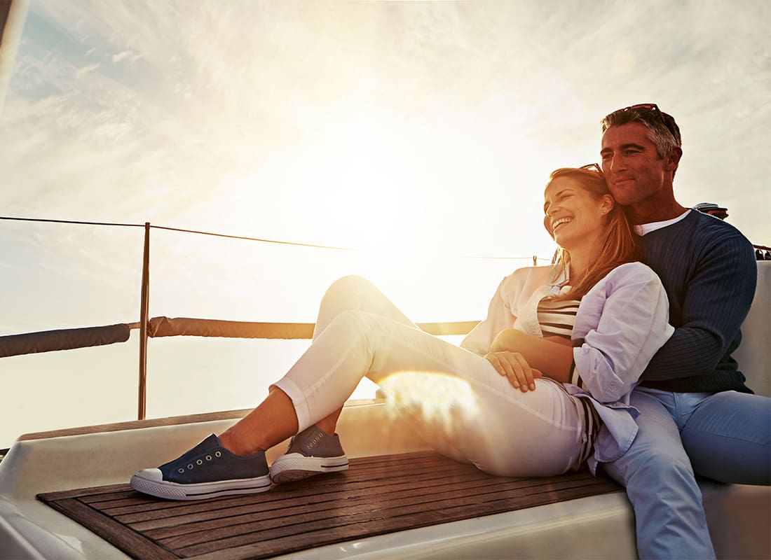 Personal Insurance - Portrait of a Middle Aged Cheerful Couple Sitting on a Yacht While on Vacation at Sunset